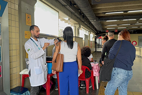 Fotografia de pessoa profissional da saúde aplicando vacina em pessoa na estação do MetrôRio.